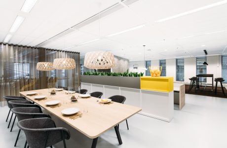 Modern, open-plan office space with large dining table, pendant lighting, and sleek furnishings.