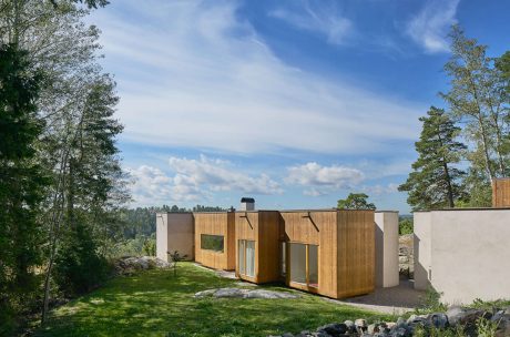 Contemporary wooden house with large windows set in a natural landscape.