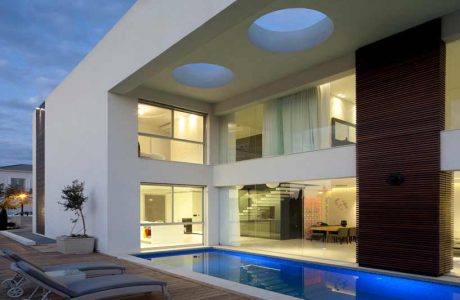 Modern, minimalist home with glass walls, pool, and skylights creating a bright, open design.