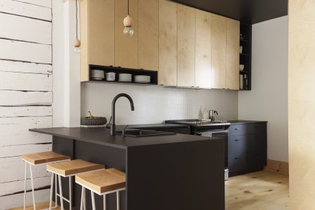 Modern kitchen with wood cabinets, black countertop, and pendant lighting.