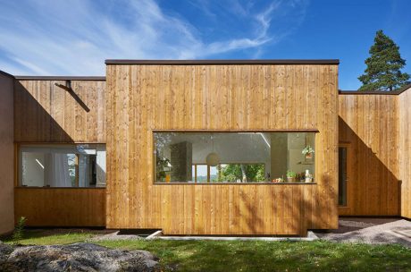 Contemporary wooden-clad house with large windows and angular design.