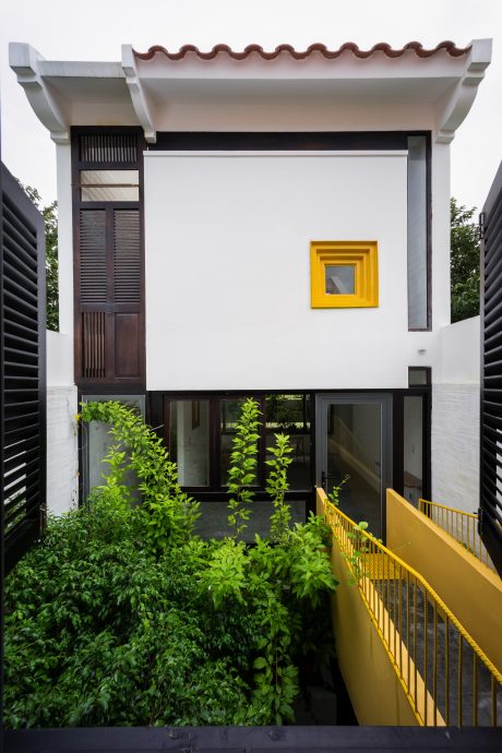 Striking modern architecture with a vibrant yellow entry and lush greenery.