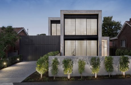 Modern concrete and glass structure with well-landscaped exterior and lighting.