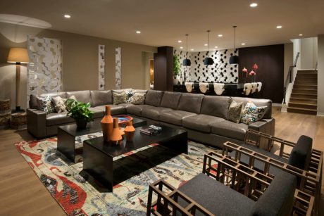 Sleek, modern living room with plush sectional, vibrant rug, and eclectic wall accents.