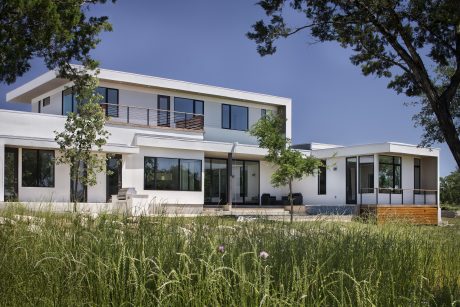 Two-story modern home with clean lines, large windows, and a grassy yard.