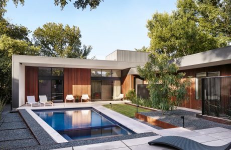 Sleek modern architecture with a minimalist pool, lounge chairs, and lush greenery.