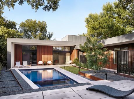 Sleek modern architecture with a minimalist pool, lounge chairs, and lush greenery.