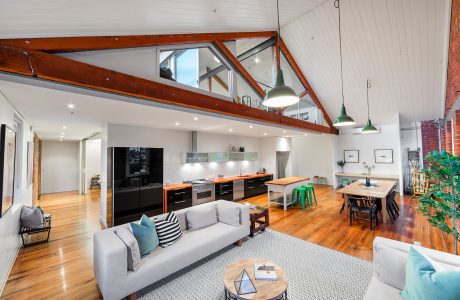 Open-concept modern loft with high ceilings, exposed beams, and integrated kitchen.