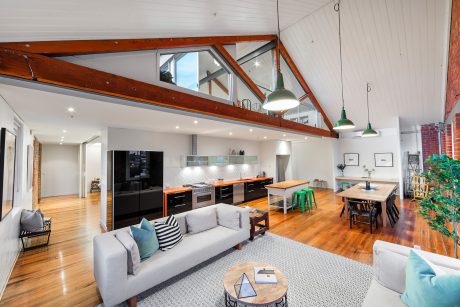 Open-concept modern loft with high ceilings, exposed beams, and integrated kitchen.