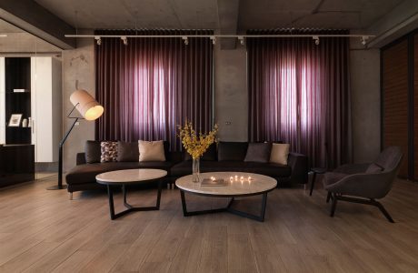 Cozy living room with plush sofas, round coffee tables, and elegant purple curtains.