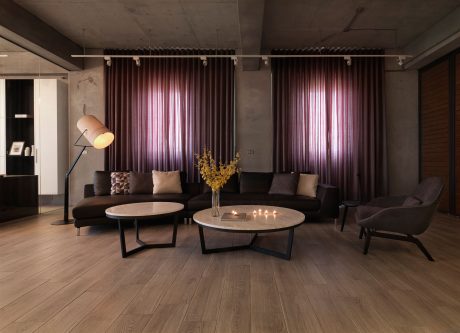 Cozy living room with plush sofas, round coffee tables, and elegant purple curtains.