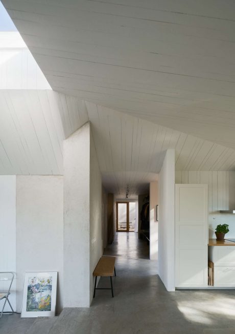 Minimalist interior with white walls, sloped ceiling, and long corridor.