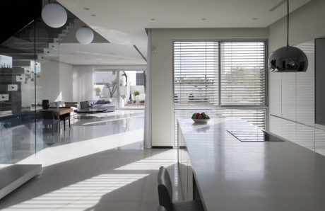 Spacious, modern kitchen with sleek white cabinets, pendant lights, and large windows offering natural light.