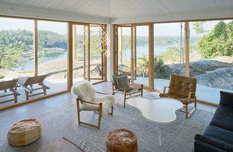 Sunlit room with modern furniture and large windows overlooking a lake.