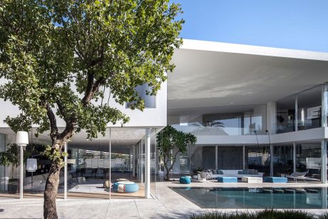 Contemporary architectural design with a large glass facade, pool, and lush greenery.