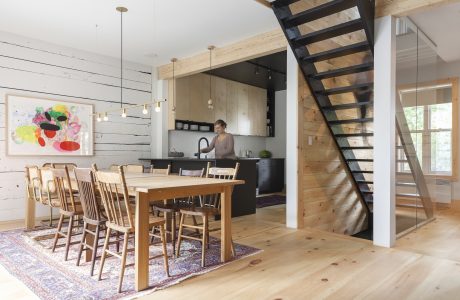 A rustic and modern open-plan kitchen with wood beams, a metal staircase, and an artistic painting.