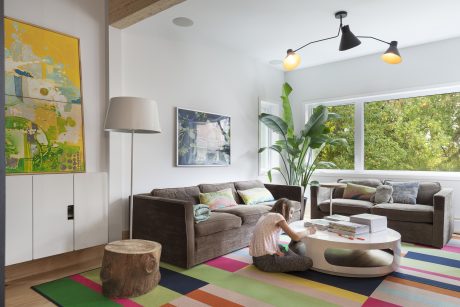 Bright, modern living room with colorful abstract art, plush sofas, and tropical plant decor.