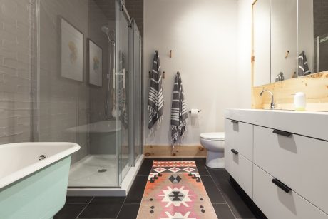 Sleek, modern bathroom with teal tub, patterned floor tiles, and minimalist vanity.