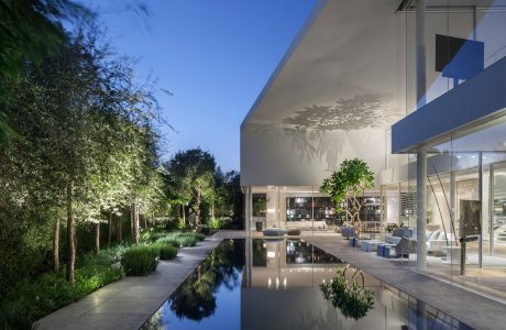 Serene, modern outdoor living space with a reflecting pool, lush greenery, and architectural details.