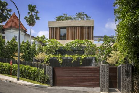 A modern, wooden-clad structure with a tiled roof, surrounded by lush greenery.