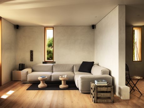 Minimalist living room with wooden floors, neutral-toned sofa, and natural light from windows.