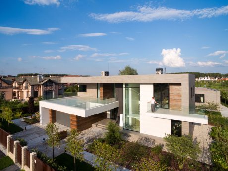 Striking modern architecture with glass walls, wooden accents, and a rooftop balcony.