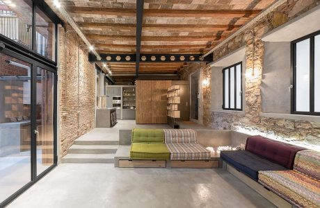 Rustic brick and wood beamed ceiling frame an open, minimalist living space with custom built-ins.