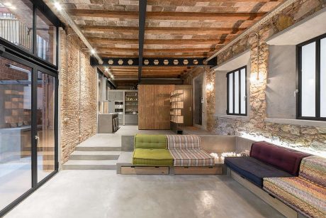 Rustic brick and wood beamed ceiling frame an open, minimalist living space with custom built-ins.