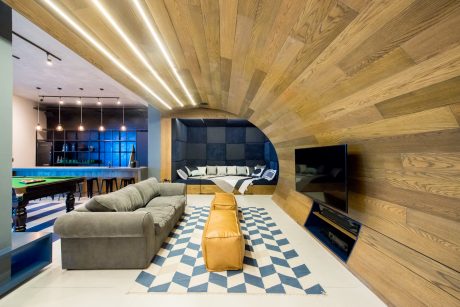 Warm-hued wood paneling, checkerboard flooring, and a modern, minimalist layout characterize this space.