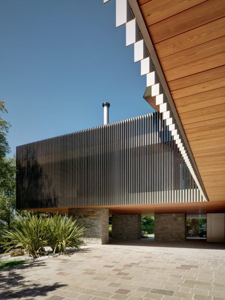 Sleek, modern exterior with wooden siding, metal railings, and a paved patio.