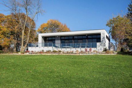 Modern, glass-enclosed building surrounded by lush greenery and colorful autumn trees.