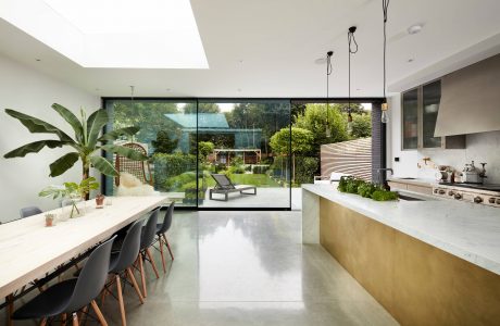 Open-concept kitchen and dining area with large glass windows overlooking lush greenery.
