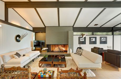 Warm, mid-century modern living room with fireplace, wood beams, and eclectic decor.