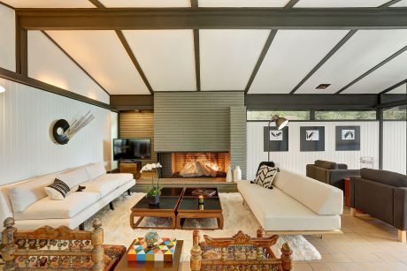 Warm, mid-century modern living room with fireplace, wood beams, and eclectic decor.