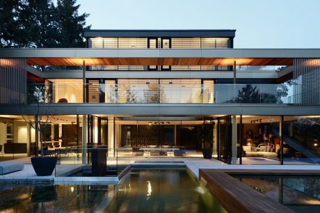 Contemporary home design with sleek lines, glass walls, and a serene pool surrounded by wooden decking.