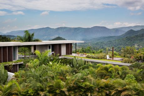 A modern tropical villa nestled in lush greenery, with expansive views of the hills.