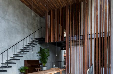 Rustic wood paneling, minimalist concrete staircase, and a sleek wooden dining area.