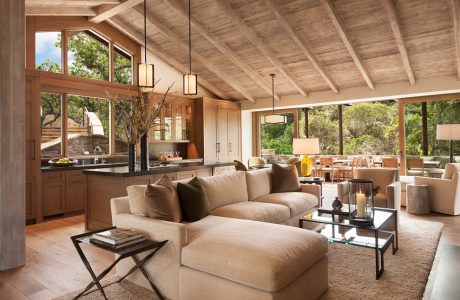 Rustic wooden ceiling beams, expansive windows, and an open-concept living area with contemporary furnishings.