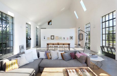 Bright, airy room with high ceilings, large windows, and neutral-toned furnishings, creating a modern, inviting space.