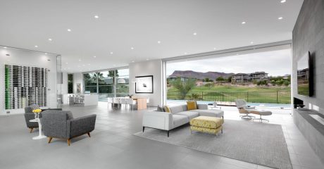 Large, modern living room with expansive windows overlooking a grassy, mountainous landscape.