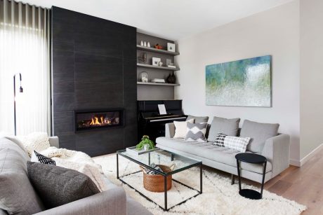 Modern living room with sleek fireplace, built-in shelves, and abstract artwork.