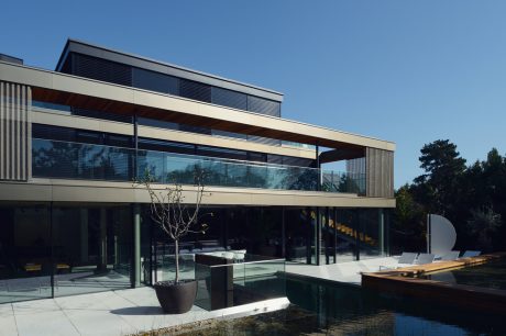 Modern glass and steel building with sleek architectural features, surrounded by a tranquil pool.