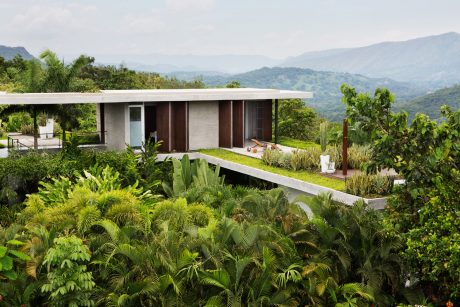 A modern, open-concept home nestled in a lush, tropical landscape with stunning views.