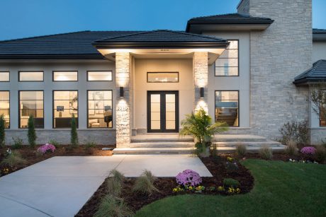 Elegant entry with stone facade, charming landscaping, and inviting lighting.