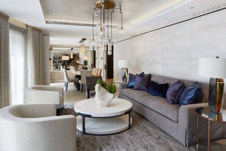 Elegant modern living room with plush gray sofa, round coffee table, and statement lighting fixture.