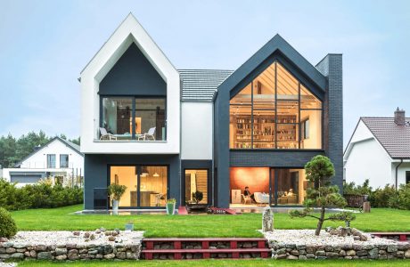 Modern, two-story house with black-and-white exterior, large windows, and an inviting library space.