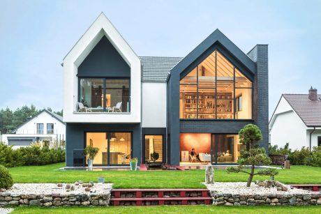 Modern, two-story house with black-and-white exterior, large windows, and an inviting library space.