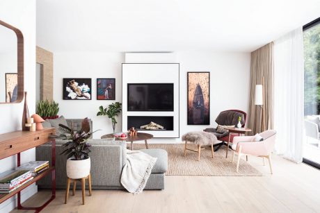 Modern living room with wood floors, plush seating, and framed artwork on walls.