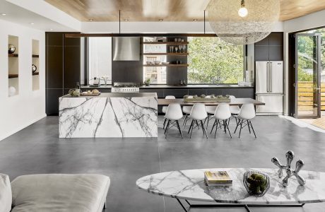 Spacious, modern kitchen with marble island, hanging light fixture, and clean lines.