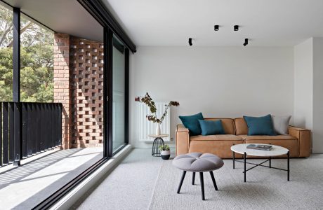 A modern, minimalist living space with brick accent wall, leather sofa, and round coffee table.